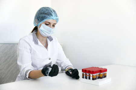 lab technician with tube of blood sample and rack with other samples. lab technician holding blood tube sample for studyの写真素材