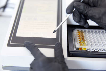 Lab Worker Adding and analyzing Liquid to Test Tubesの写真素材