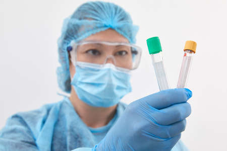 Female scientist holding two test tubes in laboratory doing research and analysis. Healthcare and...