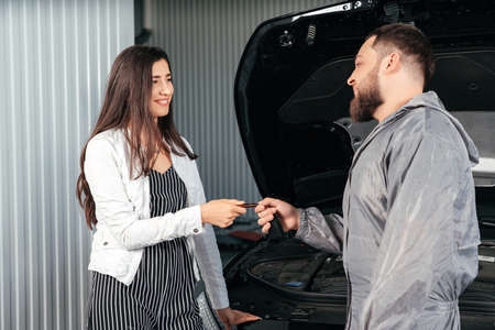 Man giving client keys to her repaired car in auto repair serviceの写真素材