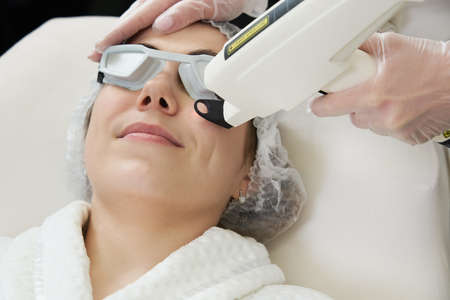 Young woman receiving laser treatment in cosmetology clinicの写真素材