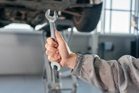 Car repair, maintenance and vehicle inspection concept. Man holding wrench in front of a carの写真素材