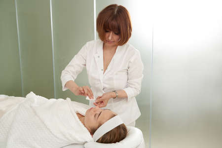 Doctor puts needles into female face on the acupuncture treatment therapy in spa salon. Alternative...