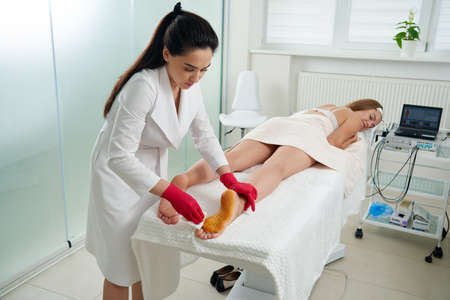 Doctor preparing to make injections of botulinum toxinon in female feet against hyperhidrosis, excessive sweatingの写真素材