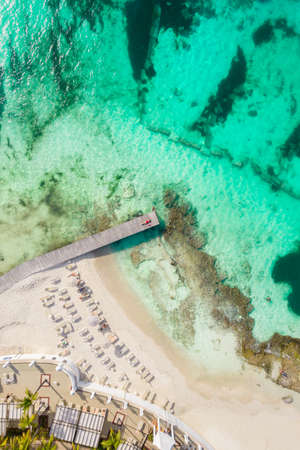 Aerial high top view of woman laying on wooden pier at sunny summer day in Cancun, Mexico, top view. Young sexy woman in the red swimsuit in summertime in Caribbean. Summer beach vacation conceptの写真素材