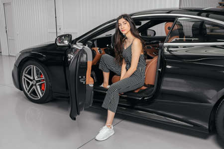 Young asian woman sitting in luxury car in garage before starting engineの写真素材