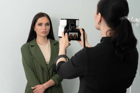 Doctor taking picture of female patient before aesthetic treatment on white background with 3d...