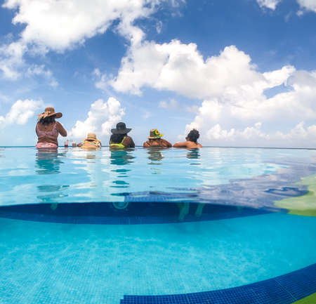 Half underwater split image of young women having fun in hotel pool in Caribbean sea. Concept of vacation and bachelorette pool partyの写真素材