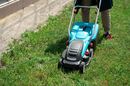 Man mowing the grass with an electric lawnmower