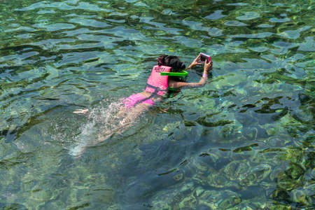 Girl wearing life jacket snorkeling in ocean clear waterの写真素材