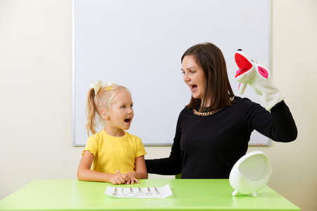 Speech therapist working with little girl in office training pronunciationの写真素材