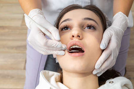 Dentist examining patient teeth with dental mirror