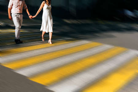 Caucasian couple holding hands crossing city intersection with motion blur effectの写真素材