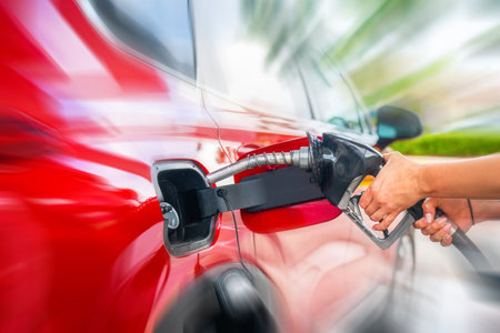 Female Hand with fuel pistol and red car with motion blur effectの写真素材