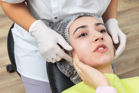 Dentist looks at a jaw of female patient checking the biteの写真素材