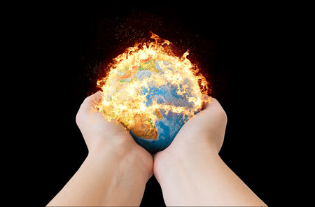 Hands holding a small globe model in fireの写真素材