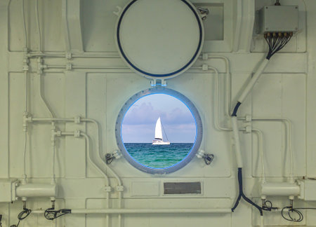 Close up view of porthole on a cruise ship with ocean and yacht viewの写真素材