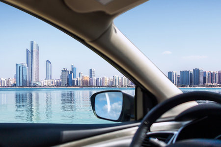 Abu Dhabi city view with water and blue sky, view through car windowの写真素材