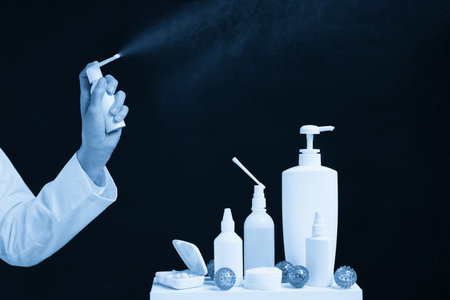 Doctor using spray sanitizer over black background, virus or germ conceptの写真素材