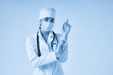 Young doctor putting on surgical gloves over white backgroundの写真素材