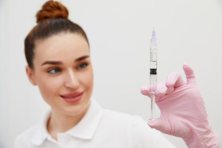 Cosmetologist holds syringe for injection with collagen hyaluronic filler for face or lips rejuvenationの写真素材