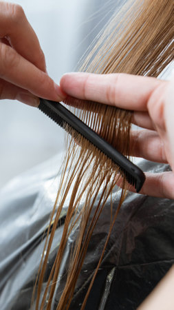 Hairdresser cut hair of a blonde young woman in hair salonの写真素材