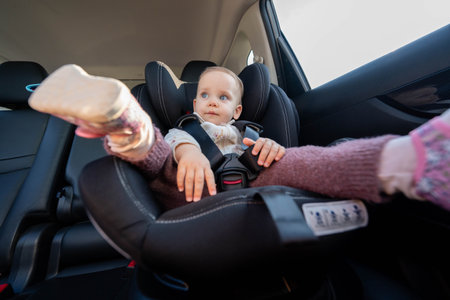 Baby safely seated in car seat for road trip. Concept of secure travel for children in vehicles