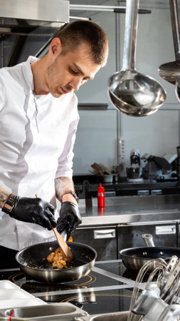 Professional chef cooks shrimps in frying pan with olive oil in restaurant kitchenの写真素材