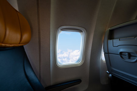 Scenic view from airplane window seat during flight above clouds. Concept of sky journey and air...