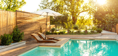 Luxury Pool with Wooden Lounge Chairs and Palm Trees at Dusk. Concept of high-end comfort and...