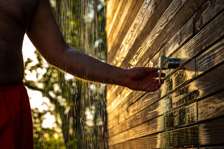 Man uses outdoor shower at sunset. Concept of summer restの写真素材