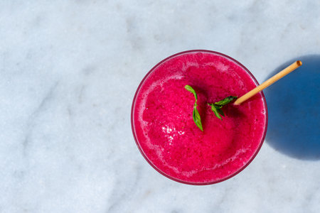 Top-down view of red frozen drink with mint on marble. Concept of refreshing summer beverage and tropical vibesの写真素材