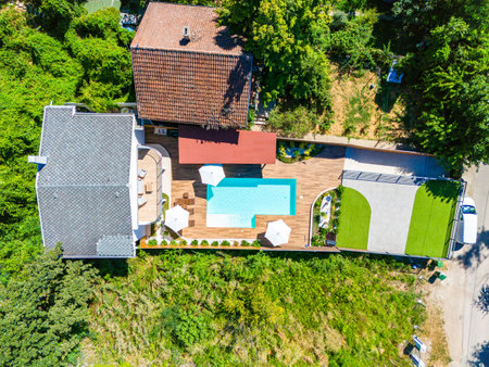Aerial view of a modern backyard with a swimming pool, green lawn, and cozy patioの写真素材