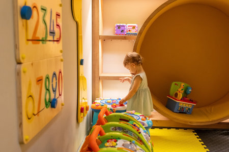 Toddler discovering toys in a sunny playroom. Concept of early education and creative growthの写真素材