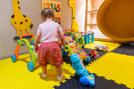 Little girl practicing cleaning skills with a toy vacuum cleaner in a bright and playful indoor playroomの写真素材
