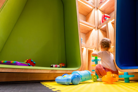 Little child enjoying creative playtime with a toy vacuum cleaner in a bright and interactive playroomの写真素材