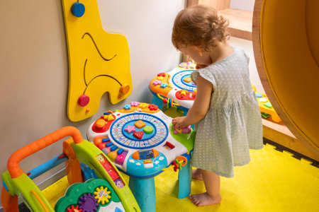 Toddler playing with colorful educational table in playroom. Concept of interactive learning and creativityの写真素材