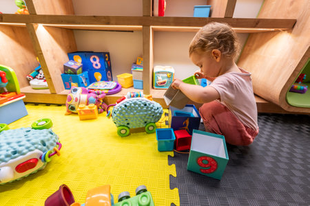 Child exploring toys and building blocks in a bright and interactive play areaの写真素材