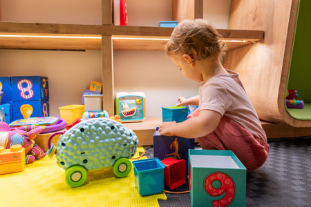Young toddler playing with colorful blocks and engaging toys in a learning spaceの写真素材