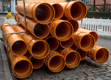 orange PVC pipes stacked in construction siteの写真素材