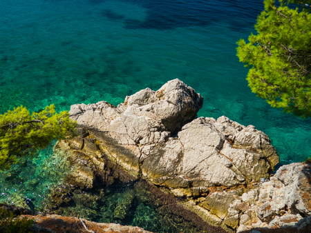 Huge rock fragment in the turquoise water with trees around, Sveti Stefan, Montenegroの写真素材