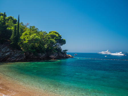 beautiful beach with different shades of turquoise water, forest on the coast and yacht on the water, Montenegro, Sveti Stefanの写真素材