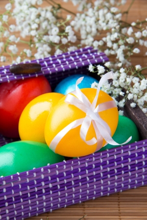 Colored painted eggs in a lilac basket の写真素材