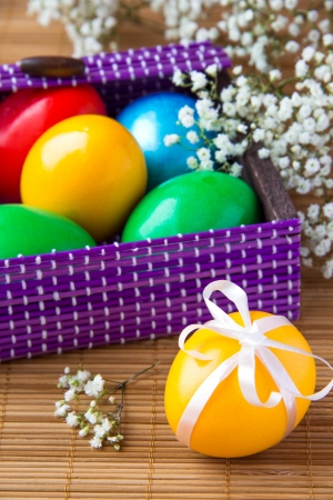 Colored painted eggs in a lilac basket の写真素材