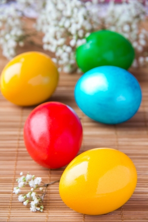 colored painted eggs on bamboo table の写真素材