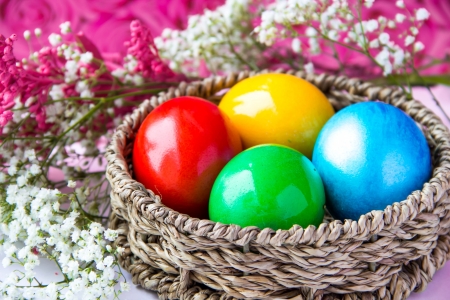 Colored painted eggs in a wattled basket with flowers の写真素材