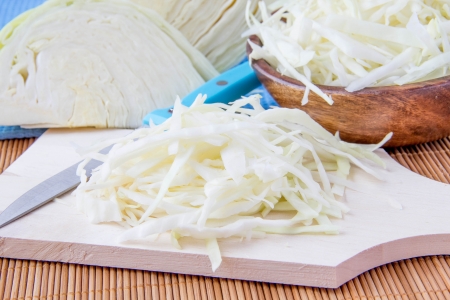 Shredded white cabbage in wooden bowl and on boardの写真素材