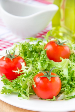 Frizzy crisp lettuce salad with cherry tomatoes on white plateの写真素材