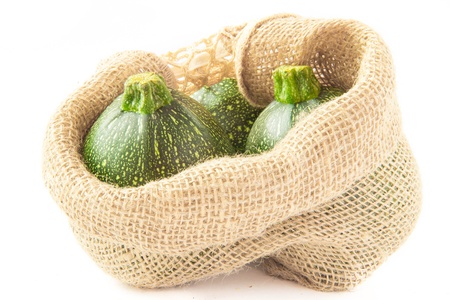 Round green zucchini in ackcloth bag on whiteの写真素材