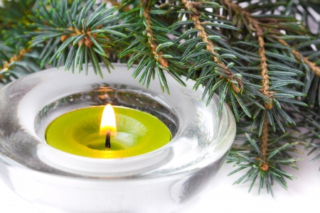 Green candle with flame and branch of Christmas treeの写真素材